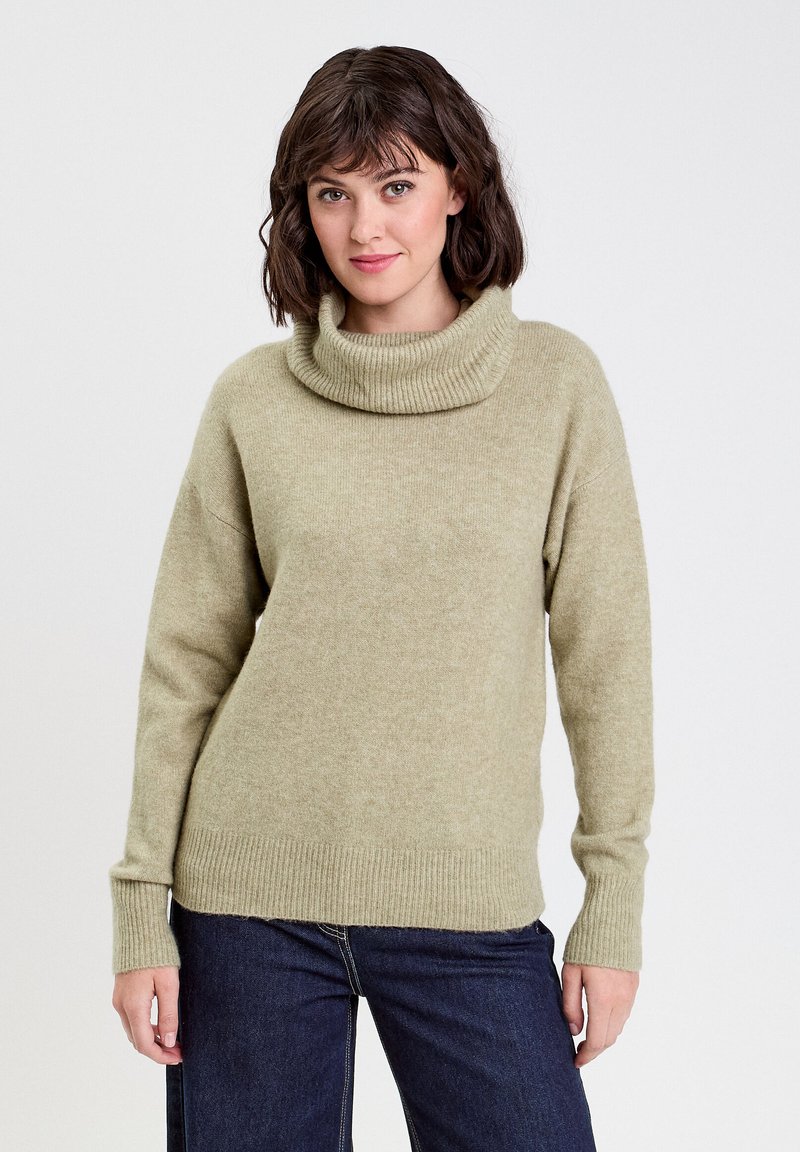 Pull à col roulé vert clair en tissu doux, avec des poignets et un ourlet côtelés, à coupe décontractée et épaules tombantes.