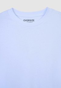 T-shirt oversized blu chiaro con scollatura rotonda, realizzato in morbido cotone; presenta un'etichetta stampata che indica "OVERSIZE."