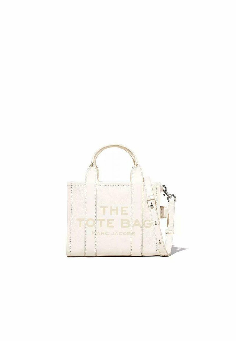 Valkoinen nahkainen olkalaukku yläkahvoilla ja irrotettavalla olkahihnalla. Sisältää kohokuvioidut tekstin "THE TOTE BAG" ja ompeluaksentteja.