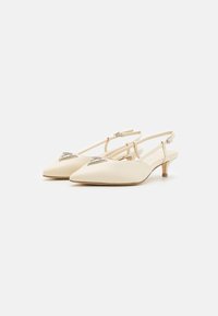 Bež ženske salonarje s peto v obliki slingback, s koničastim nosom, tankim trakom, nizko peto in dekorativnim kovinskim dodatkom na zgornjem delu. Gladka usnjena tekstura.