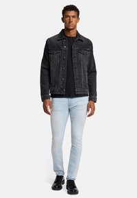 Czarna dżinsowa kurtka zapinana na guziki, dwie kieszenie na piersi, jasnoniebieskie dopasowane jeansy i czarne sznurowane buty. Lekka tekstura i dopasowany fason.