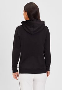 Sudadera negra de material suave, con capucha ajustable, puños y dobladillo acanalados, y un diseño simple y sin adornos.
