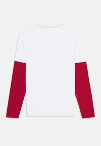Langärmliges Shirt mit einem weißen Körper und roten Ärmeln. Hergestellt aus Baumwolle, mit einem Rundhalsausschnitt und einer glatten Textur. Einfaches Design.