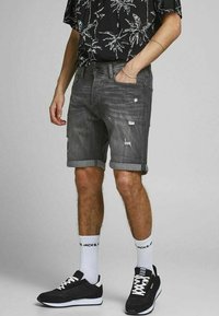 Gray denim shorts with distressed details and rolled hems, paired with a black palm tree print shirt and black athletic sneakers.