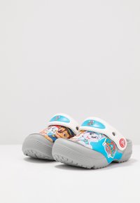 Children's clogs featuring cartoon characters, primarily in blue and grey. Made of synthetics with a textured outsole for grip.