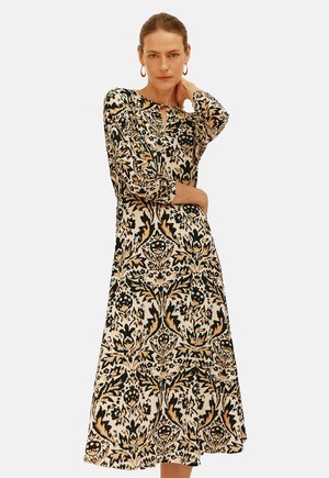 Abito a maniche lunghe con un complesso motivo nero e beige, scollatura rotonda e una vestibilità comoda che arriva appena sotto il ginocchio.