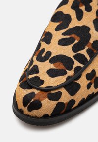 Schoen met luipaardprint, voorzien van een textuur die doet denken aan bont, zwarte decoratie en een rond te ontwerp met een platte rubberen zool.