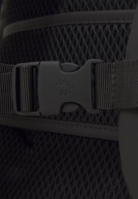 Schwarzes Netzarmband mit einer soliden schwarzen Kunststoffschnalle, die mit einem eingeprägten sechszackigen Stern-Logo versehen ist, entwickelt für einen sicheren Verschluss.