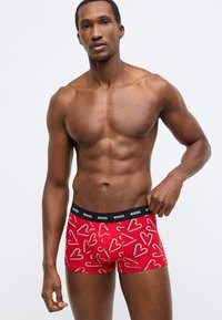 Piros boxeralsó szív és cukorpálca mintával, fekete elasztikus derékrésszel, amelyen a "DIESEL" márkanév látható.