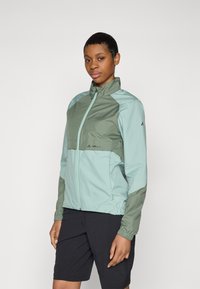 Ľahká vetrovka v mätovej zelenej a olivovej zelenej farbe. Obsahuje plný predný zips, vysoký golier a elastické manžety. Jednoduchý detail loga.