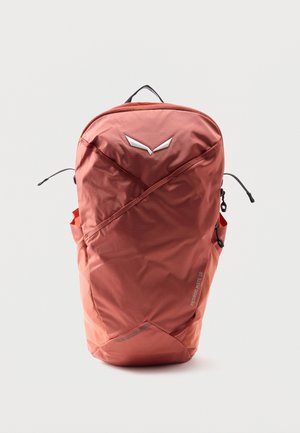 Sac à dos compact couleur rouille avec fermeture éclair diagonale à l’avant, petites poches latérales, poignée supérieure et logo réfléchissant accompagné du texte « PEDROC MATE 18 ».