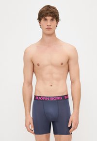 Tumedas meresinises toonis bokserpüksid, millel on sobiv disain, laia roosa vööga, millel on bold-kirjas brändinimi "BJÖRN BORG".