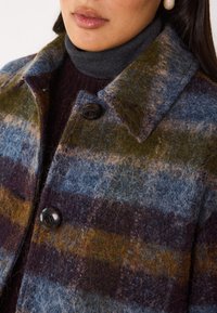 Giacca in misto lana con strisce orizzontali multicolori in blu, verde e burgundy, con colletto classico e due bottoni scuri.