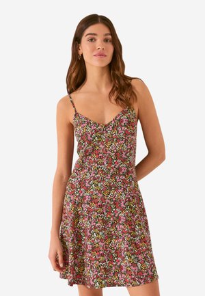 Robe d'été fleuri avec de fines bretelles en spaghetti. Présente un motif vibrant de fleurs roses et vertes sur un fond noir. Coupe évasée.