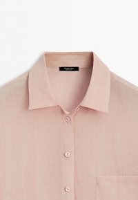 Lichtroze overhemd met knopen, kraag en borstzak, met de bovenste drie knopen zichtbaar en een zwart label aan de binnenkant van de kraag met de tekst Massimo Dutti.