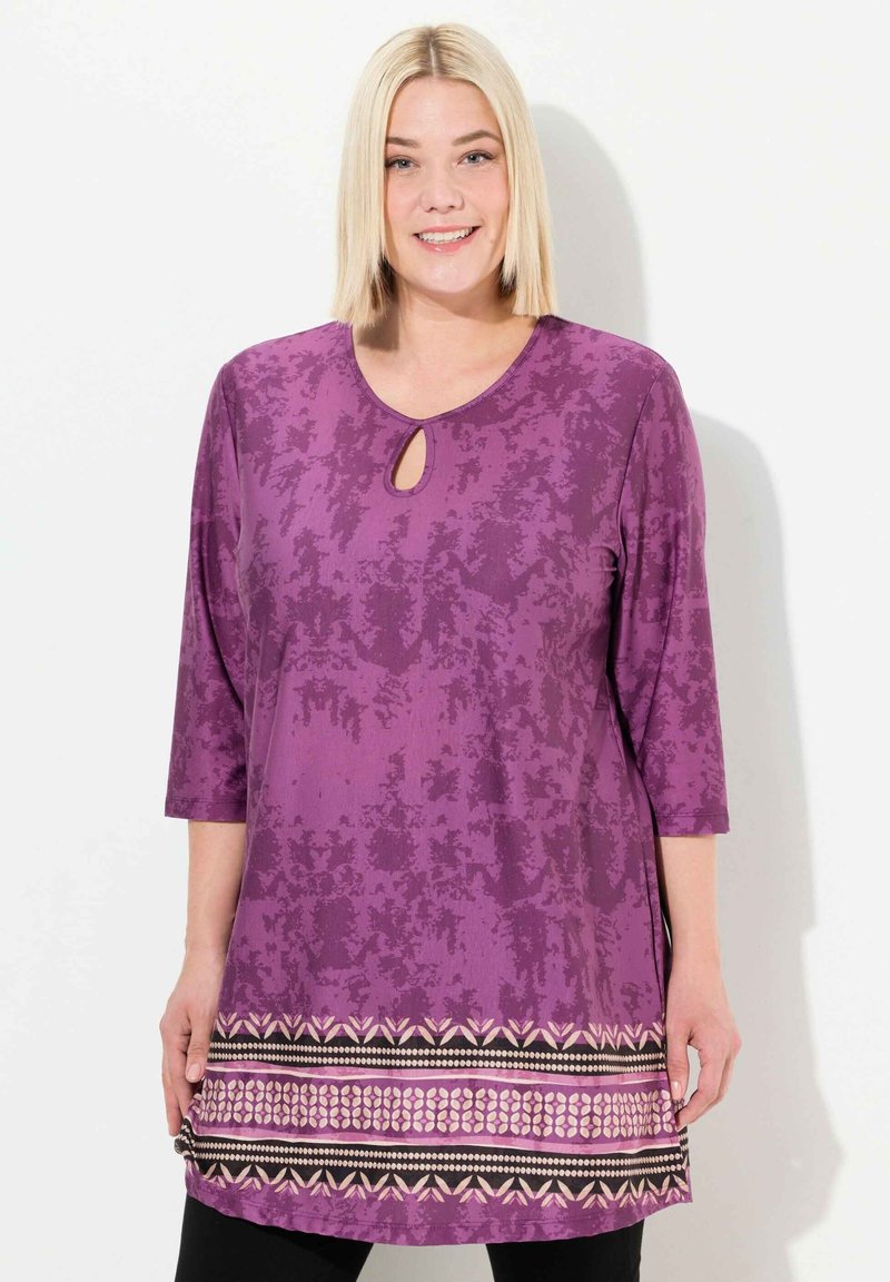 Lila Tunika mit Dreiviertelärmeln, Schlüsselloch-Ausschnitt, strukturiertem Muster und einem dekorativen Saum mit geometrischen Designs in Pink und Schwarz.