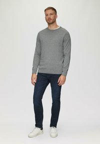 Szary sweter z dzianiny, okrągły dekolt, ściągacze przy mankietach, w zestawie z ciemnoniebieskimi dżinsami i białymi sneakersami. Prosty, teksturowany design bez wzorów.