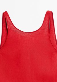 Débardeur rouge en tissu léger, doté de larges bretelles et d'une texture lisse. Il présente un col arrondi et des détails de couture minimalistes.