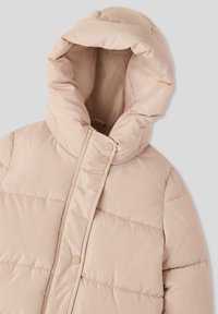 Jasno beżowa kurtka puchowa z wysokim kołnierzem i dużym kapturem. Posiada pikowane sekcje oraz beżowe napy, wykonana z gładkiego, błyszczącego materiału.