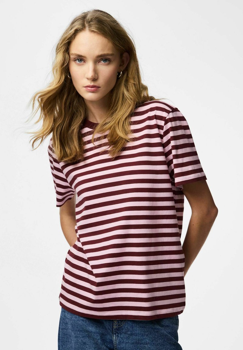 Maroon and pink striped T-shirt with short sleeves, crew neck, and soft cotton fabric. Paired with blue denim jeans.