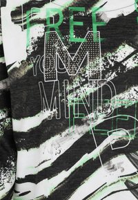 Grafisches T-Shirt mit einem schwarz-weißen und grünen Design. Der Text lautet "BEFREI DEINEN GEIST" mit einem strukturierten, gest studierten "M" und abstrakten Pinselstrichmustern.