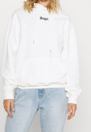 Hoodie bianco con tasca frontale, cordini e testo "Angel" in nero. Tessuto morbido e texturizzato con vestibilità rilassata. Abbinato a jeans azzurri chiari.