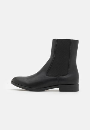 Stivale alla caviglia in pelle nera con pannelli elastici laterali, punta rotonda e tacco basso a blocco, caratterizzato da una texture liscia e un design elegante.