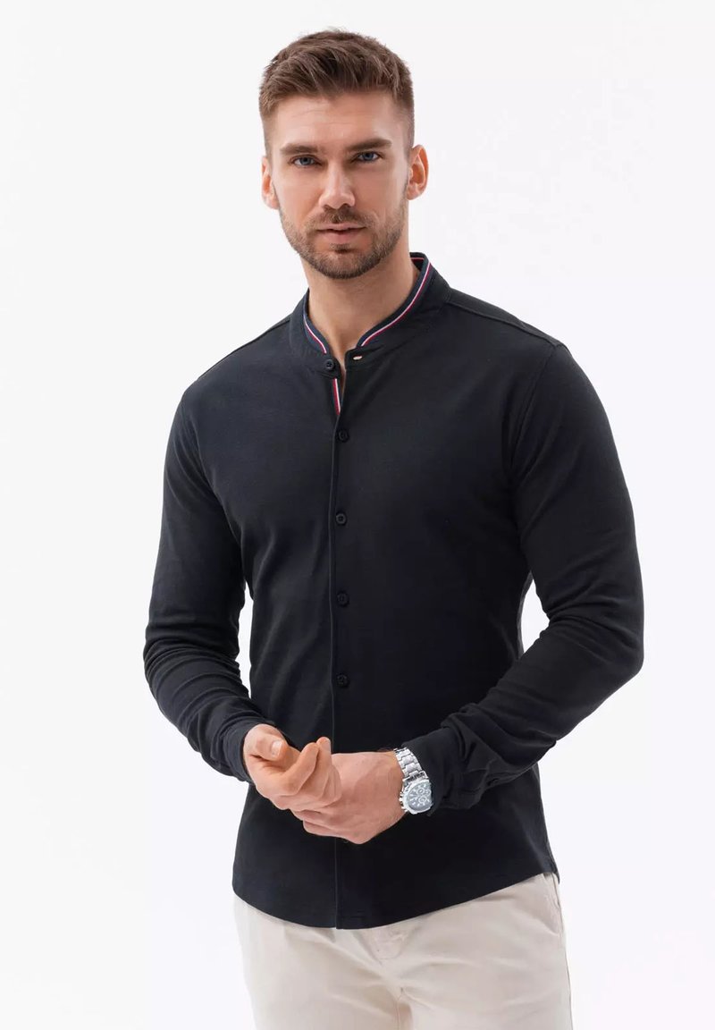 Zwarte langekleurige shirt met een mandarin-colle, voorzien van een contrasterende gestreepte rand. De stof is glad en aansluitend, met zichtbare knopen.