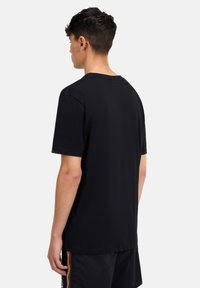 Maglietta nera a maniche corte con scollo rotondo, caratterizzata da una texture liscia e un orlo posteriore leggermente più lungo.
