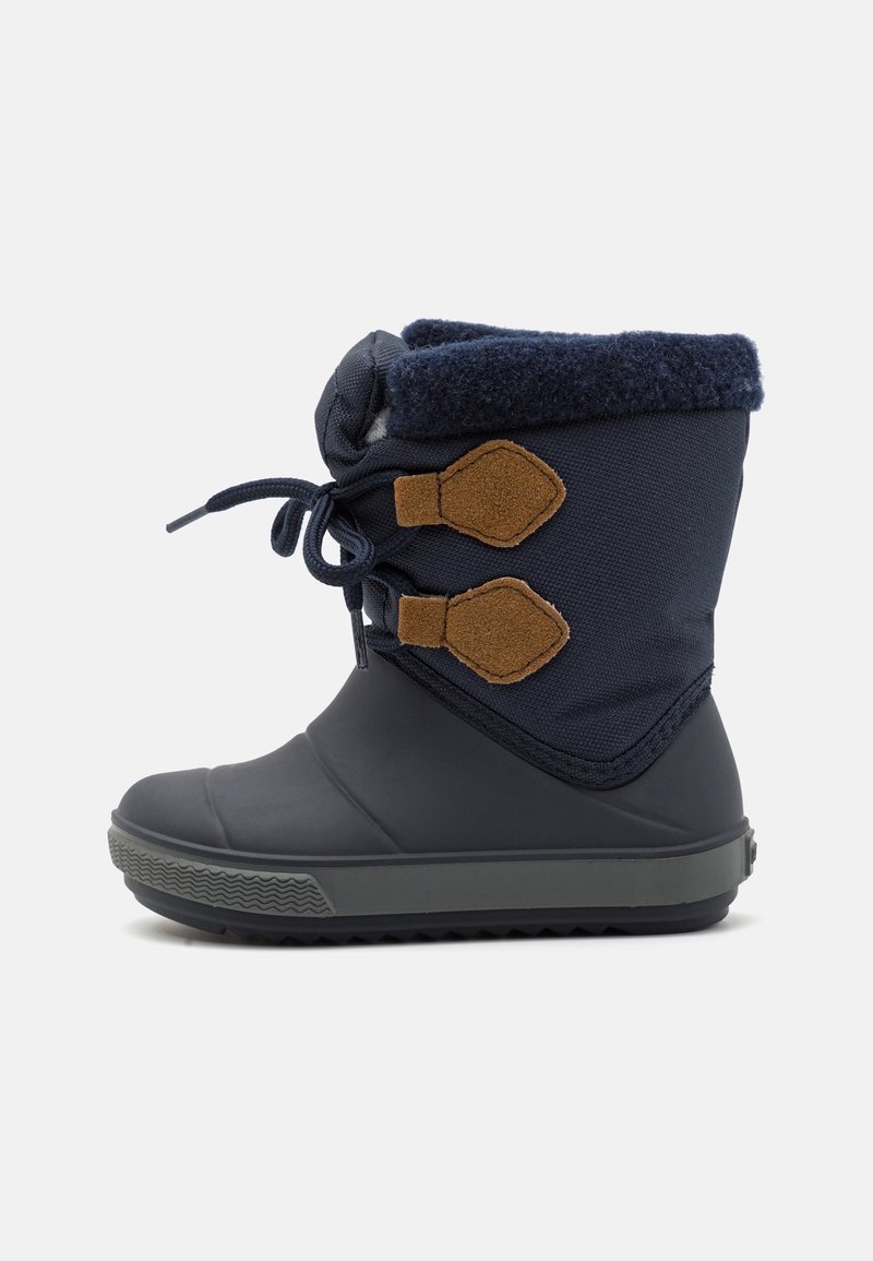 Botte d'hiver marine avec une semelle en caoutchouc, une tige texturée marine, un bord en polaire et des accents en daim marron. Dispose de fermetures à lacets et à bascule.