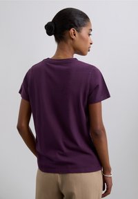 Paarse katoenen T-shirt met korte mouwen, ronde hals en een gladde textuur. Heeft een eenvoudig, onopgesmukt ontwerp zonder zichtbare merknaam.