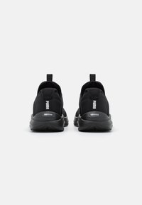 Des chaussures de sport noires avec une tige en maille, des tirettes à l'arrière et des semelles extérieures en caoutchouc. Présente le logo "PUMA" et la marque "SOFTRIDE" sur le talon.