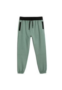 Hellgrüne Jogginghosen mit elastischem Bund, schwarzem Kordelzug und seitlichen Taschen mit schwarzen Akzenten. Am Knöchel umgeschlagen.