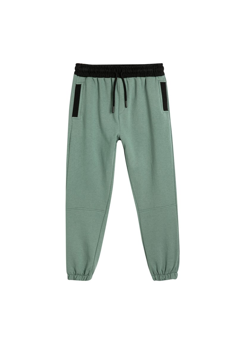 Hellgrüne Jogginghosen mit elastischem Bund, schwarzem Kordelzug und seitlichen Taschen mit schwarzen Akzenten. Am Knöchel umgeschlagen.