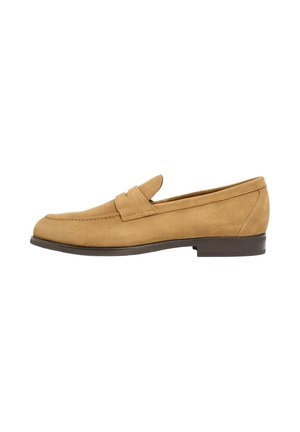 Mocassin pour homme en daim beige avec un petit talon empilé et une bride sur le dessus, présenté de profil sur un fond blanc.