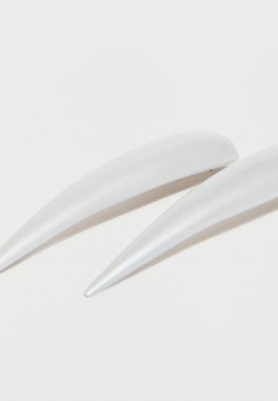 Δύο μακριά, καμπυλωτά, λευκά κλιπ μαλλιών με λείο, γυαλιστερό επιφάνεια τοποθετημένα σε λευκό φόντο.