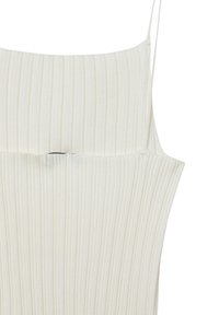 Canotta bianca a costine con spalline sottili e scollatura dritta. Il tessuto sembra morbido con sottili righe verticali.