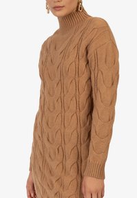 Strickpullover in Kamel mit hohen Kragen und Kabelmuster, ausgestattet mit gerippten Bündchen und einem strukturierten, warmen Stoff.