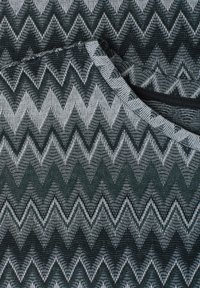 Tissu plié avec un motif zigzag chevron noir et gris en tricot texturé.