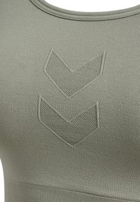 Olivgrön sport-bh i strukturerad stickad material, rund halsringning och två nedåtriktade chevronmönster framtill.