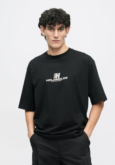 Μαύρο κοντομάνικο T-shirt από βαμβάκι, με κεντρικό λευκό λογότυπο που γράφει "HOLZWEILER WINTERSPORT" σε έντονη γραμματοσειρά.