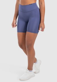 Hoge taille marineblauwe sportshorts gemaakt van rekbaar materiaal, met een gladde textuur en een aansluitende pasvorm, gecombineerd met witte sportschoenen.