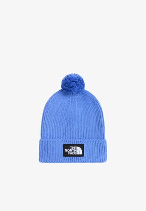 Niebieska dzianinowa czapka z pomponem i podwiniętym mankietem z czarną naszywką z białym logo „The North Face” na środku z przodu.