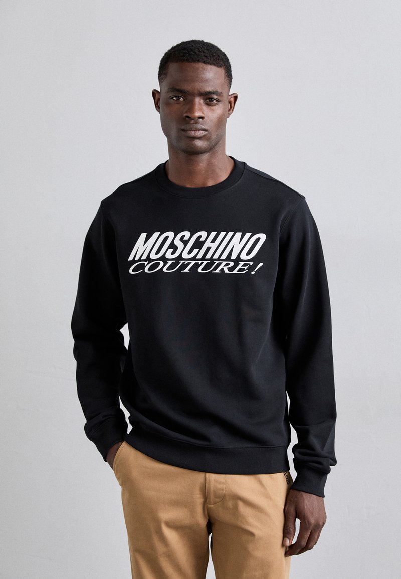 Sweatshirt noir avec le texte audacieux "MOSCHINO COUTURE!" en blanc. Confectionné en matériau doux avec des poignets et un ourlet côtelés, design ajusté.