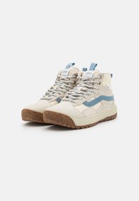 Høye sneakers i beige kanvas med blå detaljer og en teksturert brun yttersåle. Har snøring og en logo på tungen.
