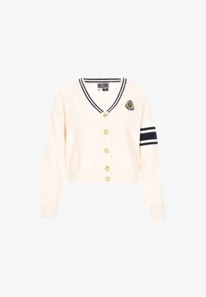 Kreemikardigan V-kaelusega, millel on nöörkimise detailid, kuldsed nööbid ja tumesinine triip varrukatel. Rindel on tikitud embleem.