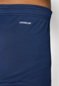 Navy blue sports shorts made of smooth, stretch fabric featuring an elastic waistband and a white "AEROREADY" logo near the top.