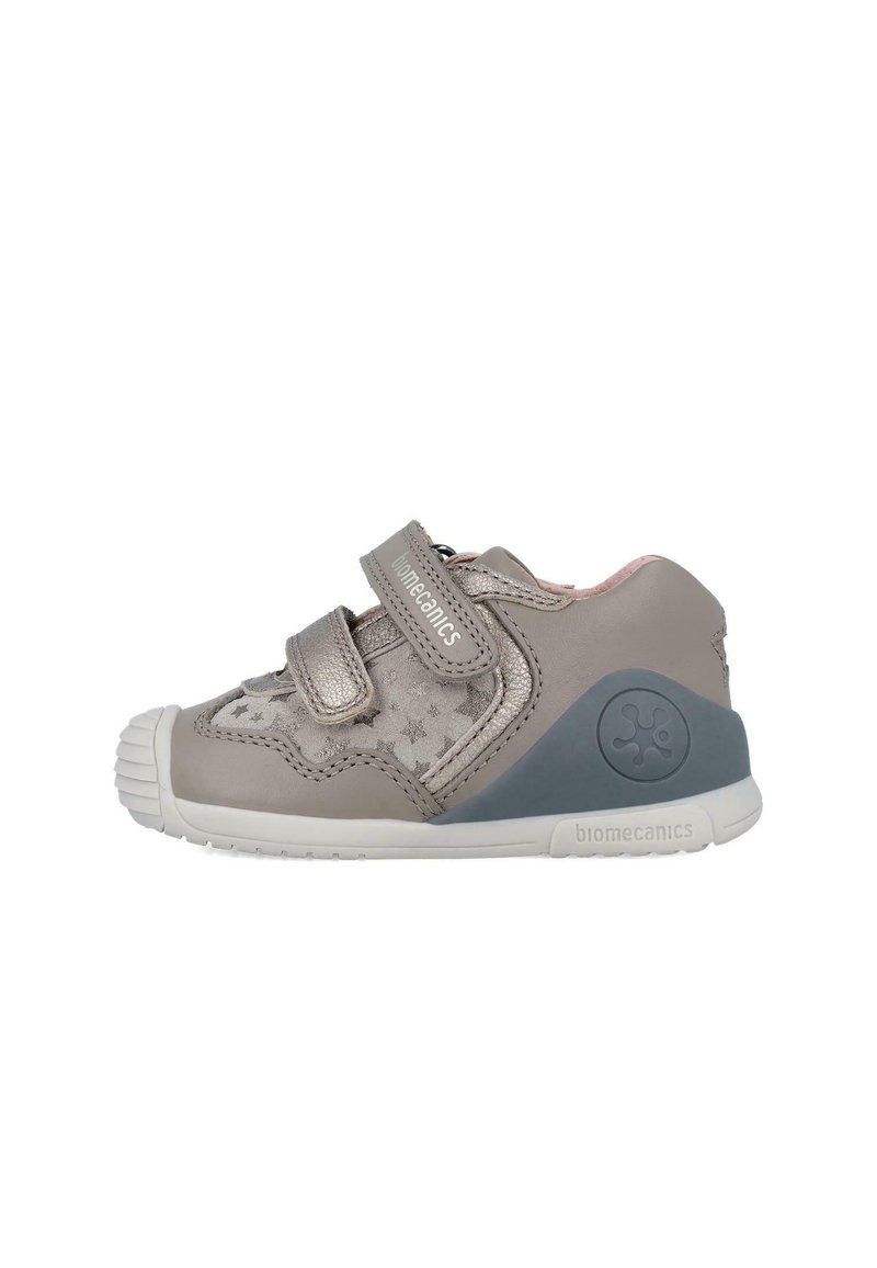 Zapato infantil de cuero gris con patrón de estrellas, doble tira de Velcro y punta de goma blanca. Presenta un acento en el talón gris y un logotipo de la marca.