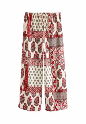 Pantalon large avec un motif patchwork rouge, noir et crème, orné de motifs floraux et géométriques, et une taille élastique à cordon.