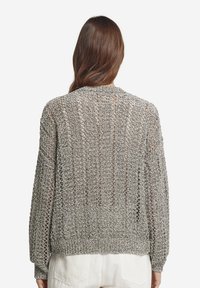 Grå stickad tröja med ett löst, öppet vävmönster, långa ärmar och ribbad nederkant. Designen har en avslappnad passform med en subtil textur.